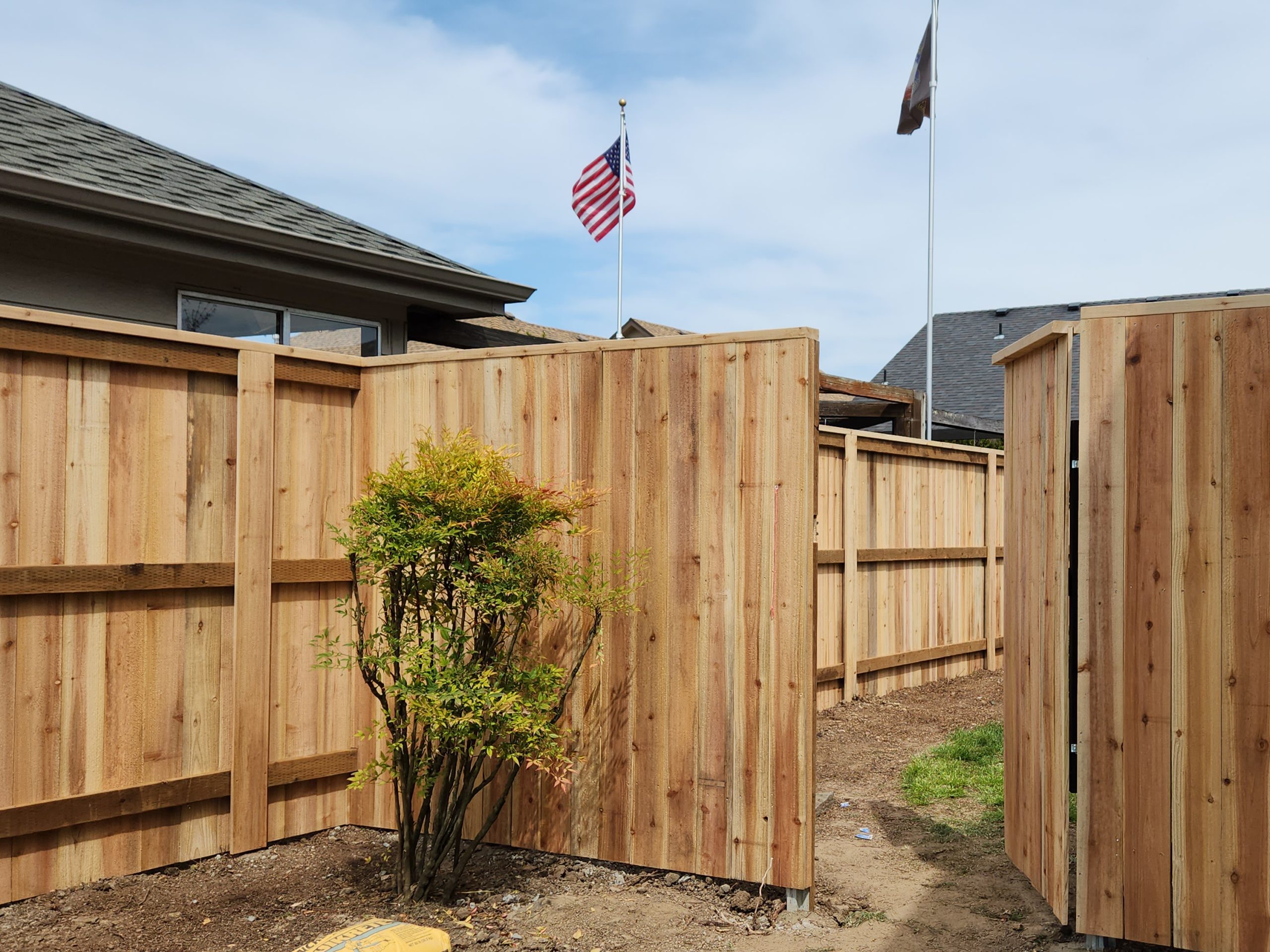 FenceCasaBellaConstruction Wooden fence by Casa Bella Construction with a gate into the backyard.